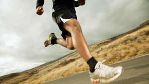 bottom half of lone runner on a road.